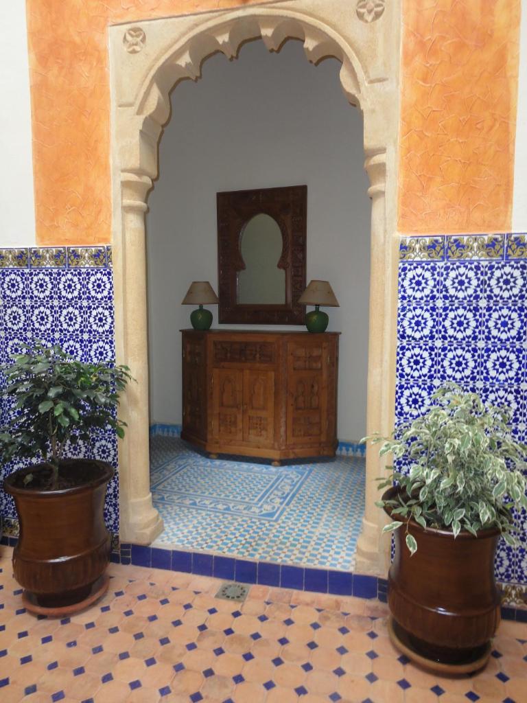 une entrée dans un bâtiment avec deux plantes en pot dans l'établissement Dar Yanis, à Rabat