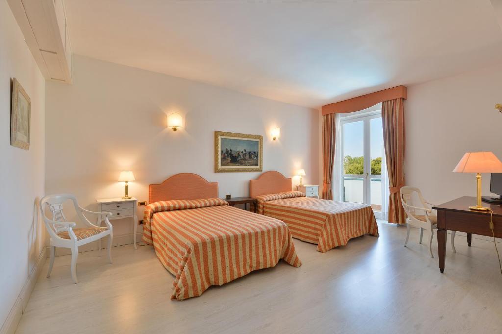 une chambre d'hôtel avec deux lits, un bureau et une fenêtre dans l'établissement Hotel Meridiana, à Paestum