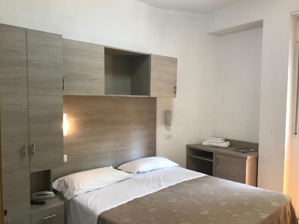 une chambre avec un lit avec une tête de lit en bois dans l'établissement Hotel Villa Enea, à Cattolica
