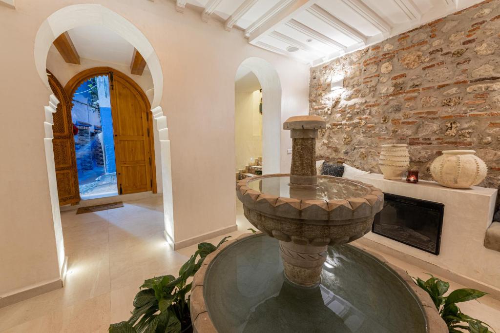 un salon avec un mur en pierre et une fontaine à eau dans l'établissement Riad Nila, à Chefchaouen 120 autres photos