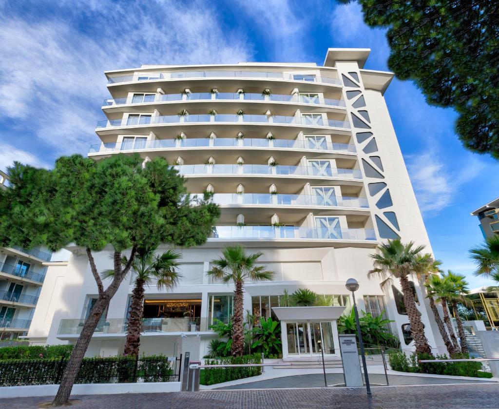 un bâtiment avec des palmiers devant dans l'établissement Hotel Sporting, à Rimini