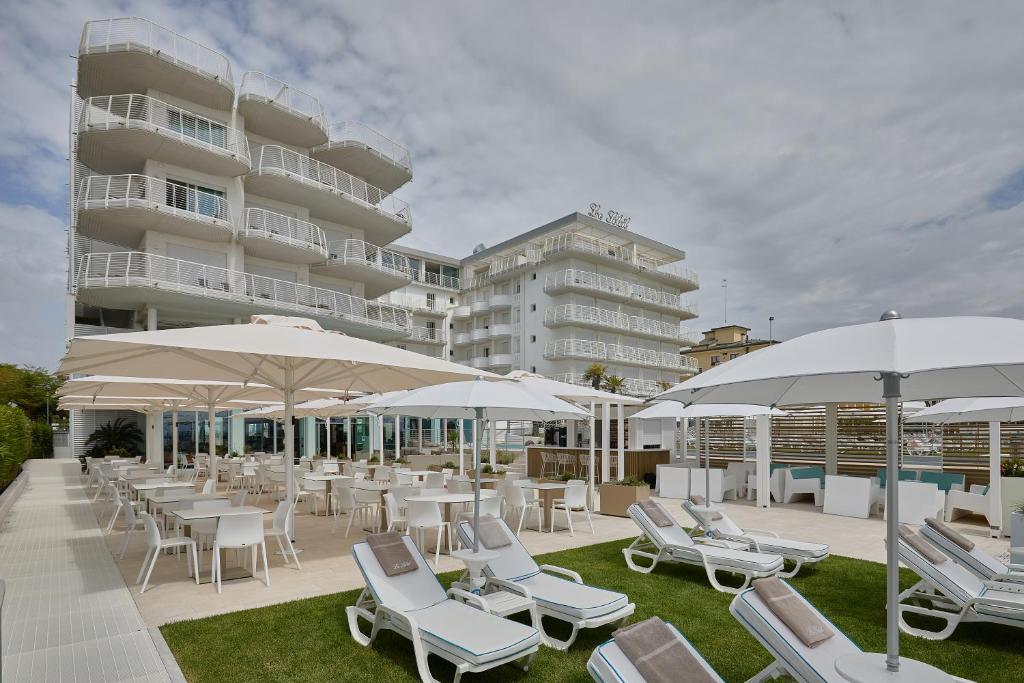 un groupe de chaises et de parasols devant un bâtiment dans l'établissement Hotel Le Soleil, à Lido di Jesolo