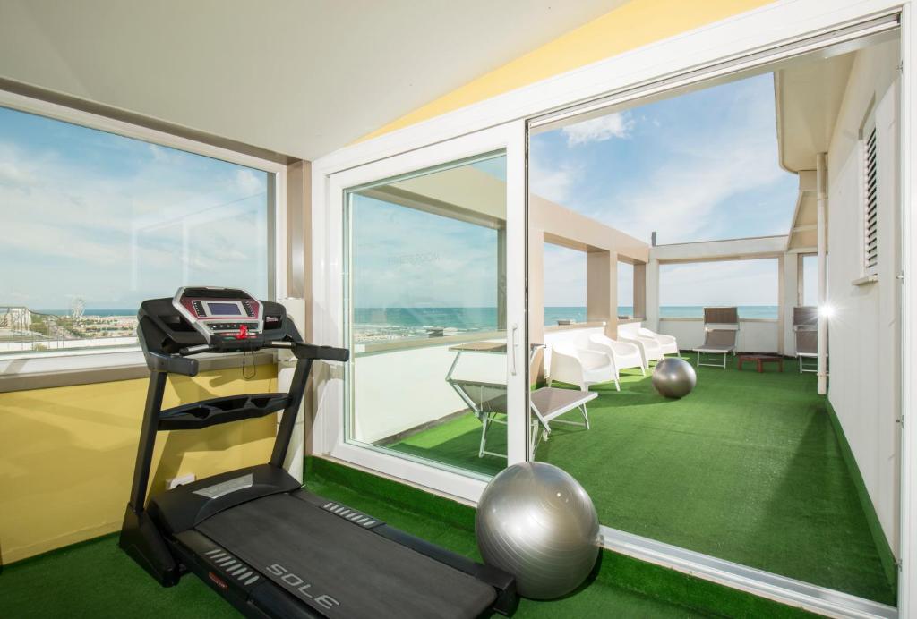 - une salle de sport avec un tapis de course dans une pièce dotée de fenêtres dans l'établissement National Hotel, à Rimini
