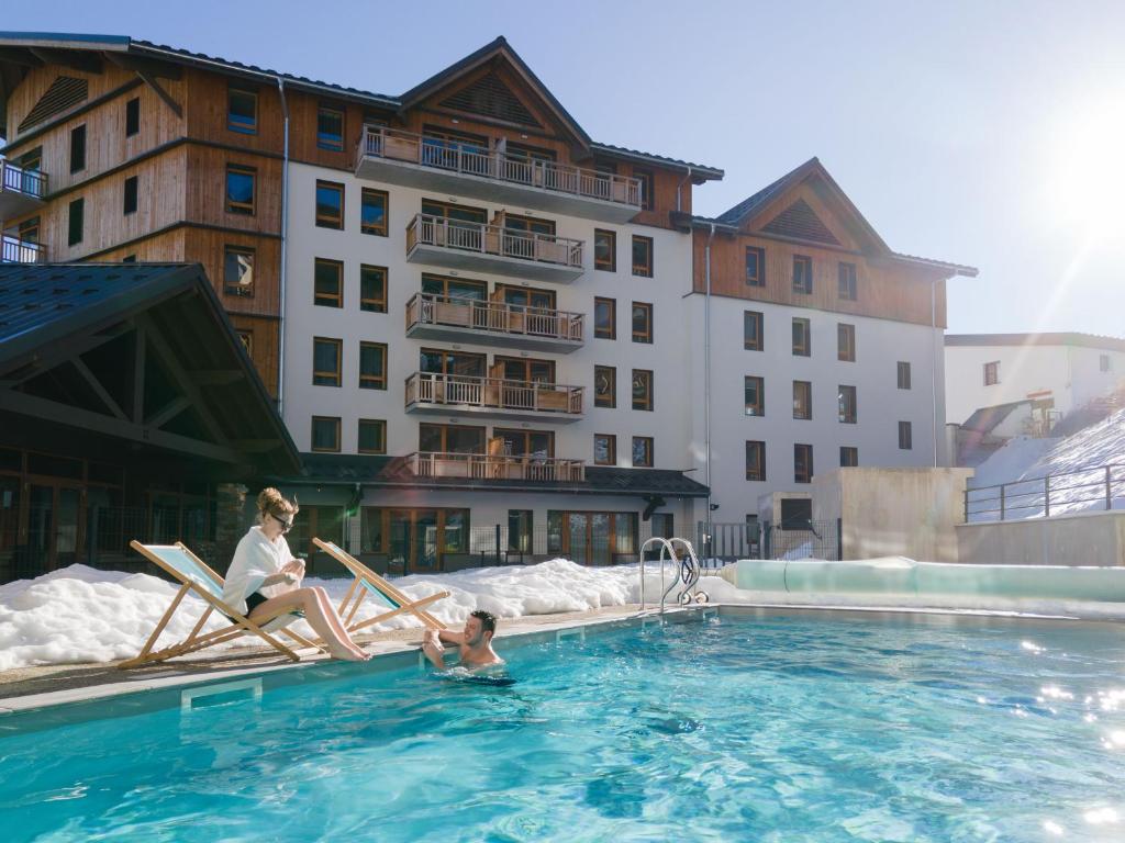 une femme et un enfant assis dans une piscine d'hôtel dans l'établissement Résidence Club MMV Les Clarines, à Les Deux Alpes