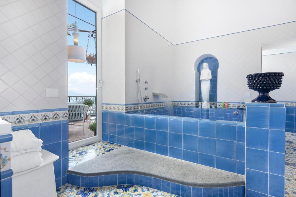 La salle de bains est pourvue de carrelage bleu au sol et d'une baignoire. dans l'établissement Hotel La Tonnarella, à Sorrente