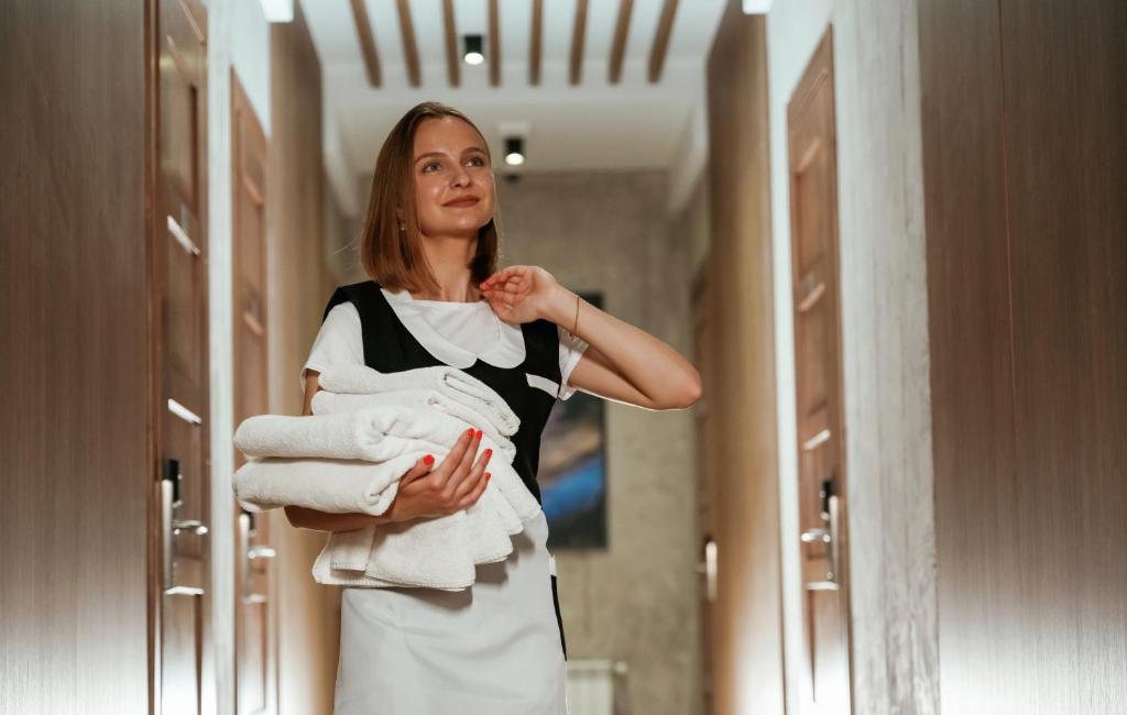 une femme tenant des serviettes devant un miroir dans l'établissement Hotel MARINELLA - Private Free Parking - Grotticelle Beach 200 m, à Capo Vaticano