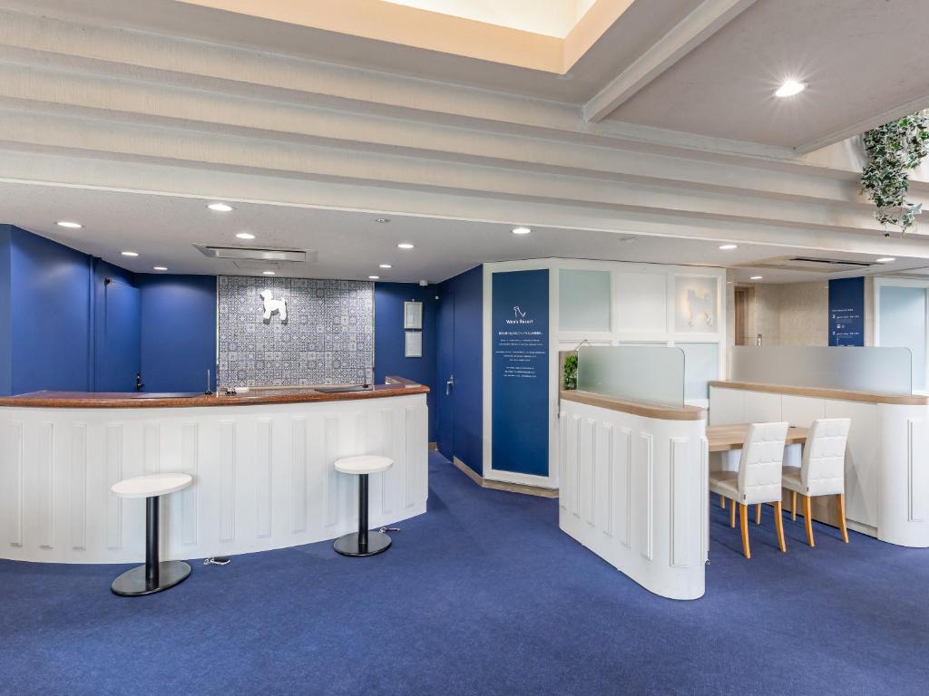 un hall d'entrée avec un bar, des tabourets et des murs bleus dans l'établissement Wan's Resort Jogasaki, à Itō
