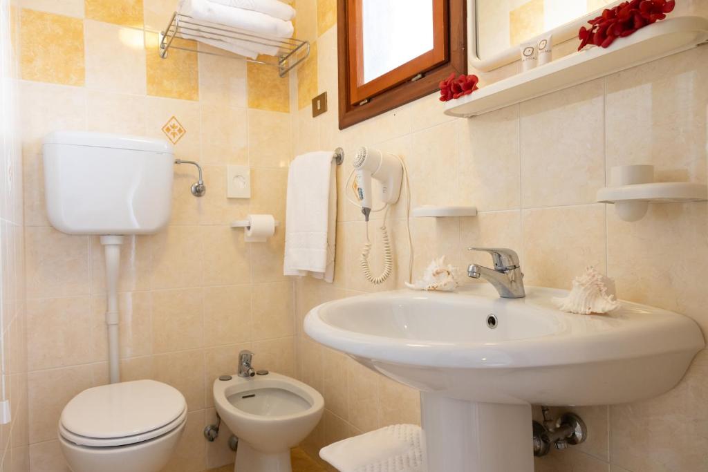 une salle de bain avec un lavabo et des toilettes et un téléphone dans l'établissement Hotel Smeraldo, à Lido di Jesolo 97 autres photos