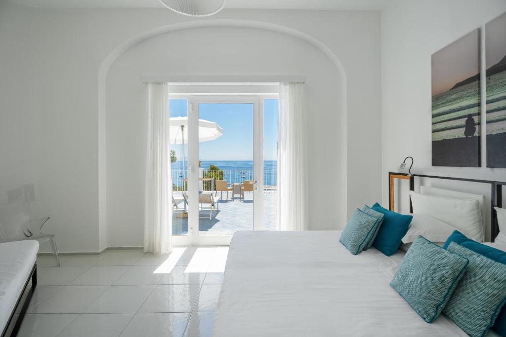 une chambre blanche avec un lit avec vue sur l'océan dans l'établissement Apollon Club & Thermal Spa, à Ischia