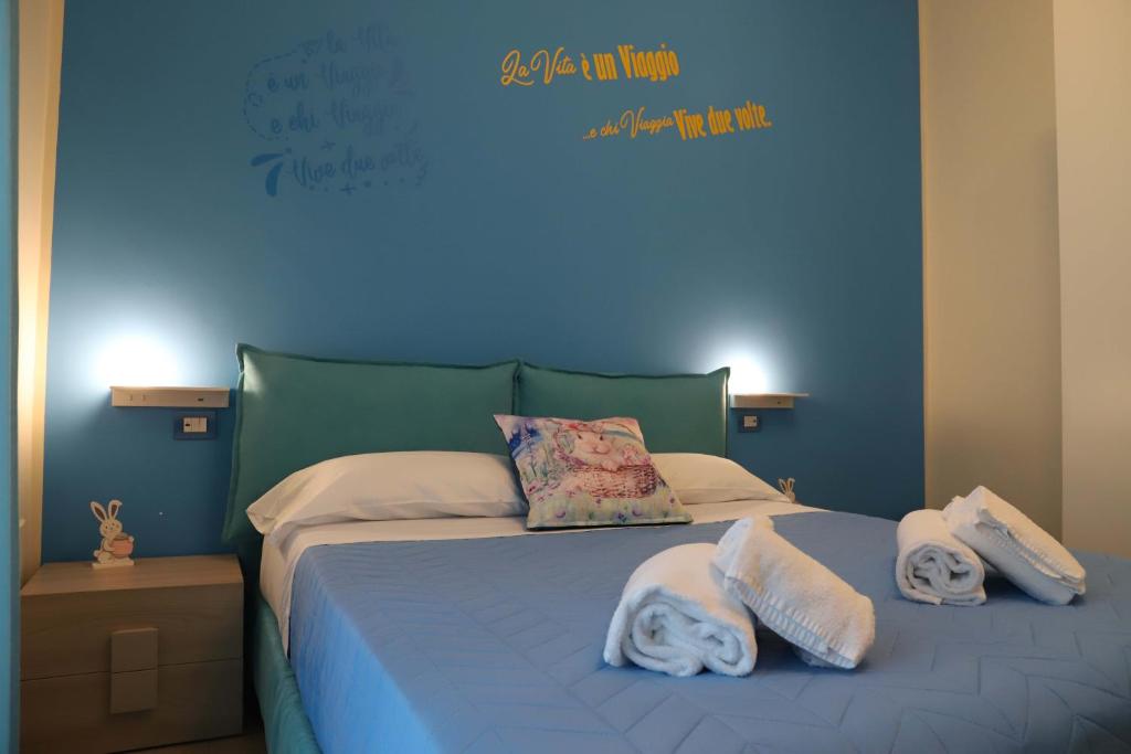 - une chambre bleue avec un lit et des serviettes dans l'établissement Domus Marina - Baltico Apartment, à Mondragone