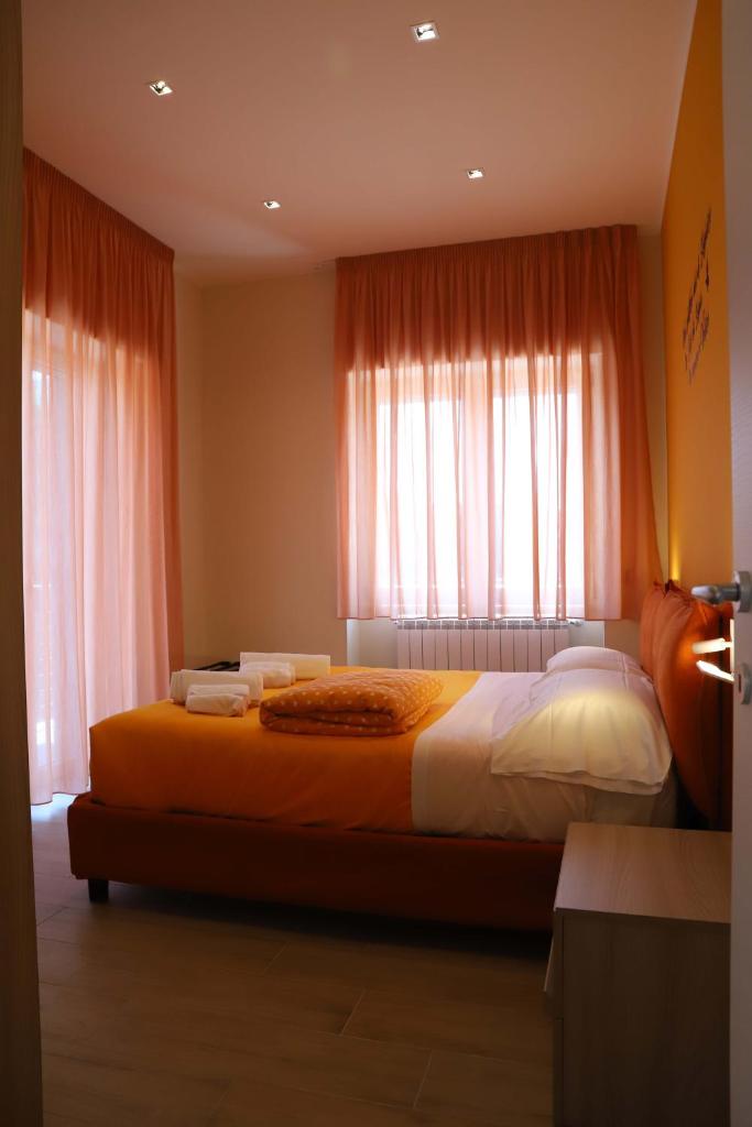 - une chambre avec un grand lit et des rideaux orange dans l'établissement Domus Marina - Egeo Apartment, à Mondragone