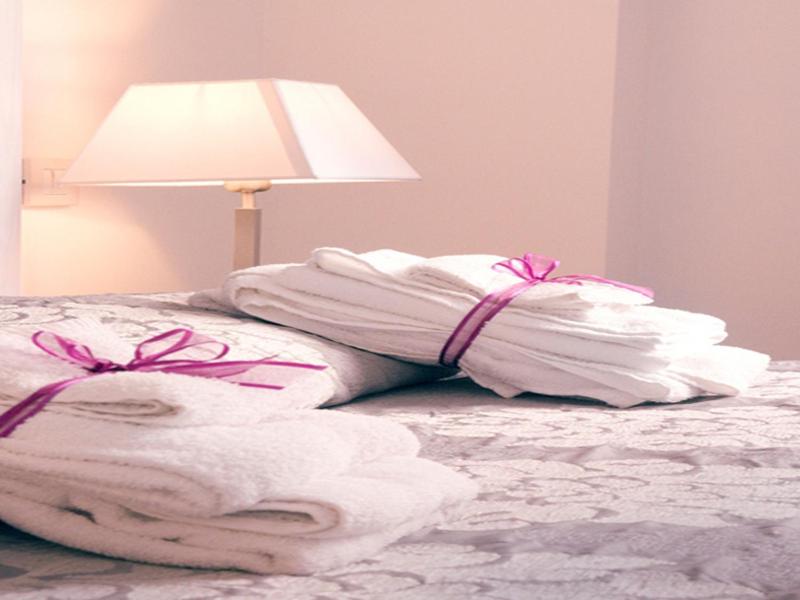 une pile de serviettes sur un lit avec une lampe dans l'établissement Hotel Giulio Cesare, à Rimini