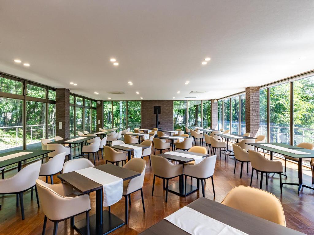 un restaurant avec des tables, des chaises et des fenêtres dans l'établissement Izumigo Yatsugatake Dog Paradise Cottage, à Hokuto