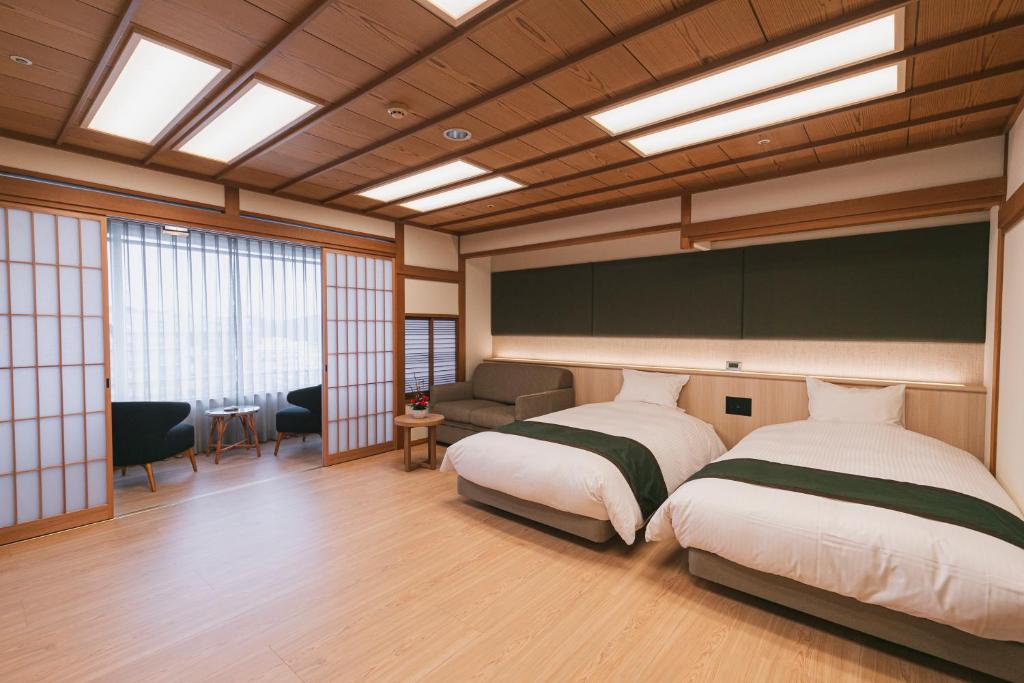 une chambre avec deux lits et un canapé dans une pièce dans l'établissement Hotel Kasuien, à Ureshino