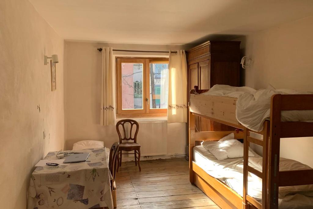 Cette chambre comprend 2 lits superposés, une table et une fenêtre. dans l'établissement Village House In The Heart Of Saint Chaffrey, à Saint-Chaffrey