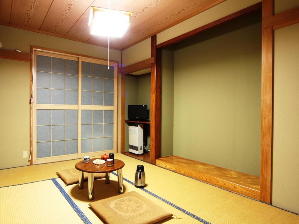 un salon avec une table et une grande fenêtre dans l'établissement Sunrise Meiji-ya, à Nozawa Onsen 22 autres photos