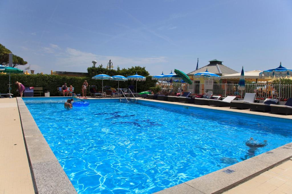 une grande piscine bleue avec chaises et parasols dans l'établissement Residence Panama, à Lido di Jesolo