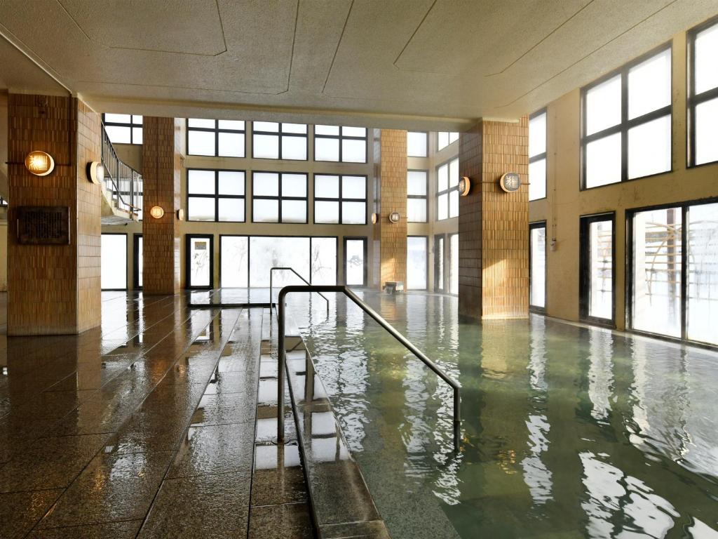 une pièce vide avec une piscine d'eau dans un bâtiment dans l'établissement jyozankei SHIKAnoYU, à Jozankei