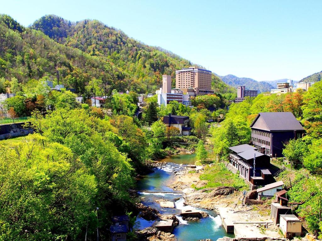 une ville avec une rivière, des bâtiments et des arbres dans l'établissement jyozankei SHIKAnoYU, à Jozankei