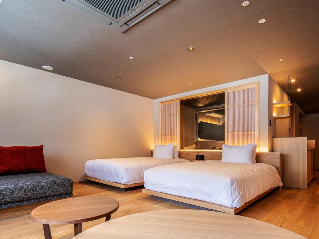 deux lits dans une chambre avec un canapé et une table dans l'établissement HanaMOMIJI, à Jozankei 65 autres photos