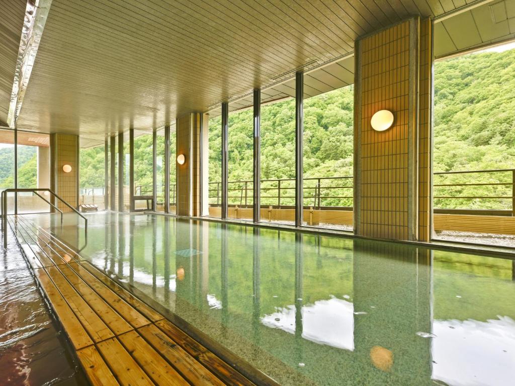une piscine vide avec des parois et des fenêtres en verre dans l'établissement HanaMOMIJI, à Jozankei