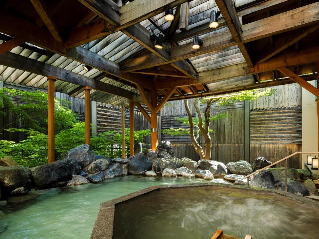 une grande piscine avec des rochers et un plafond en bois dans l'établissement HanaMOMIJI, à Jozankei