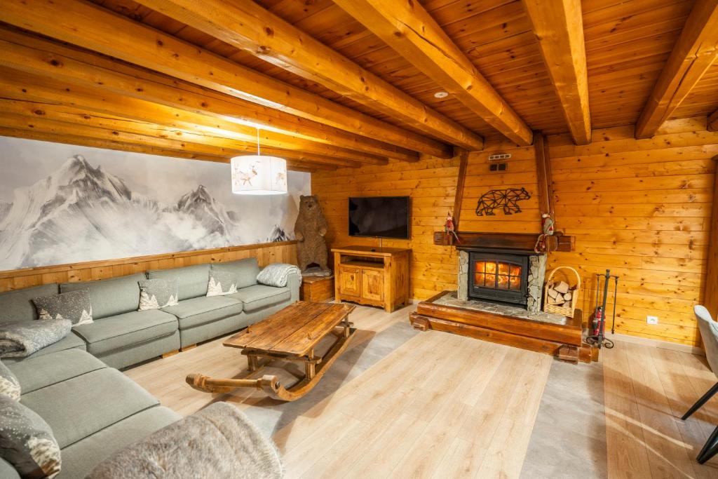 un salon avec un canapé et une cheminée dans l'établissement 2AlpesChalets - Chalet Marie 1 - Standing et Sauna au pieds des pistes, à Les Deux Alpes