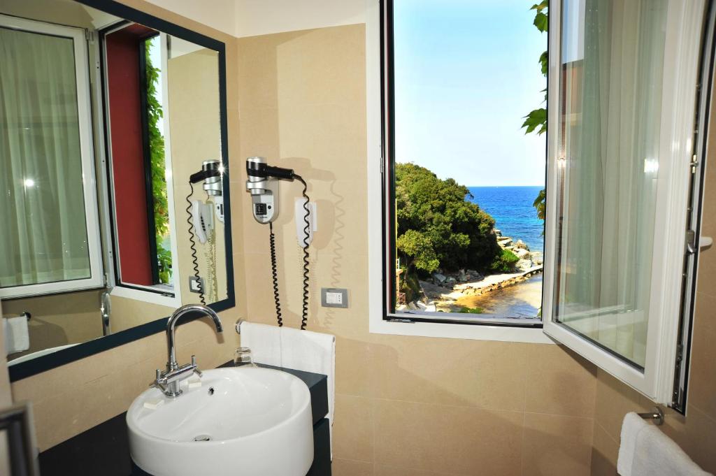 La salle de bains est pourvue d'un lavabo et offre une vue sur l'océan. dans l'établissement Hotel Desiree, à Procchio