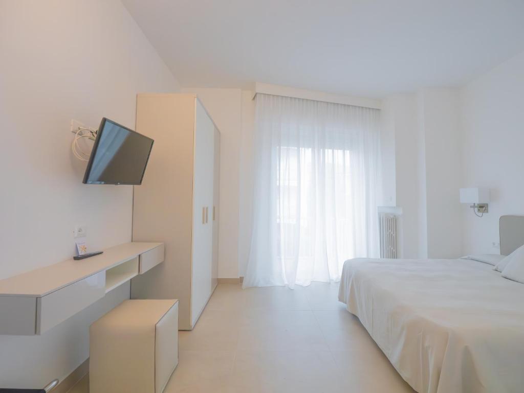 une chambre blanche avec un lit et une télévision dans l'établissement Hotel Splendid, à Diano Marina
