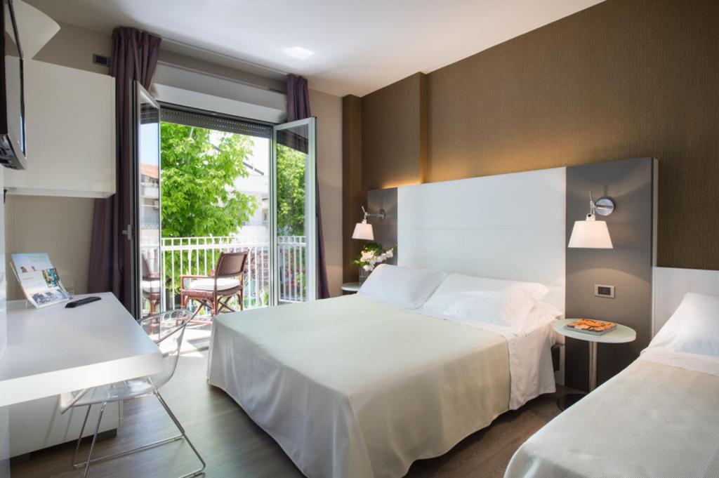 une chambre d'hôtel avec un lit et un balcon dans l'établissement Hotel Maddalena, à Riccione