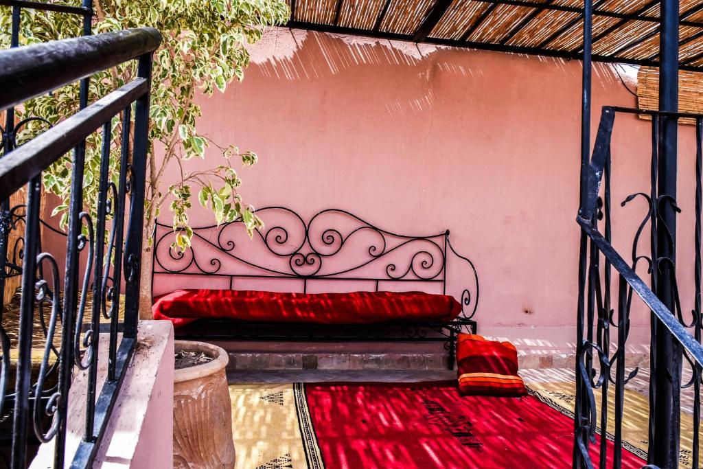 - un lit en métal avec des oreillers rouges sur une terrasse couverte dans l'établissement Dar Nineta, à Fès