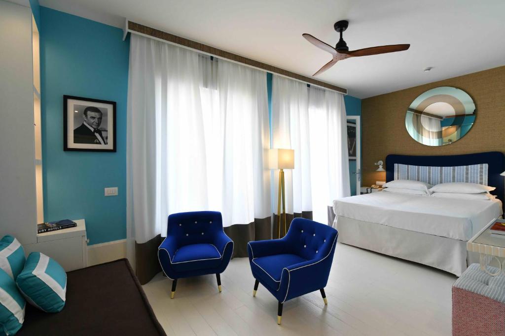 une chambre avec un lit et deux chaises bleues dans l'établissement Hotel Majestic, à Lido di Jesolo