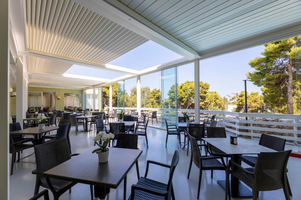 un restaurant avec des tables, des chaises et des fenêtres dans l'établissement Paglianza Hotel, à Peschici
