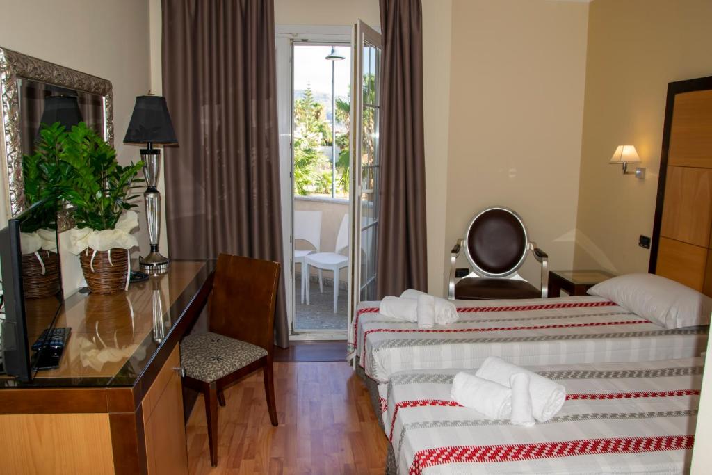 une chambre d'hôtel avec deux lits et un bureau dans l'établissement Regent Beachotel, à Reggio de Calabre