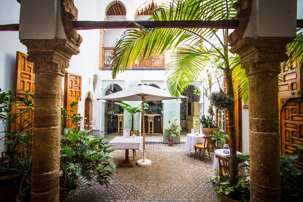 une cour avec des tables et des plantes dans un bâtiment dans l'établissement Dar Mayssane, à Rabat