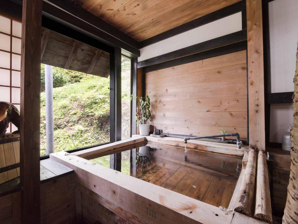 Cette chambre est dotée de murs en bois et d'une grande fenêtre. dans l'établissement Yokohama Fujiyoshi Izuten, à Itō