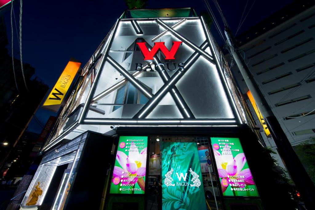 un bâtiment avec un panneau de signalisation sur son côté dans l'établissement Hotel W-BAGUS -W GROUP HOTELS and RESORTS-, à Tokyo