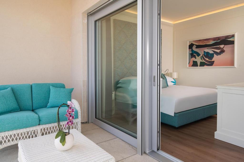 une chambre avec un canapé bleu et une chambre dans l'établissement Riviera Resort Hotel, à Lignano Sabbiadoro