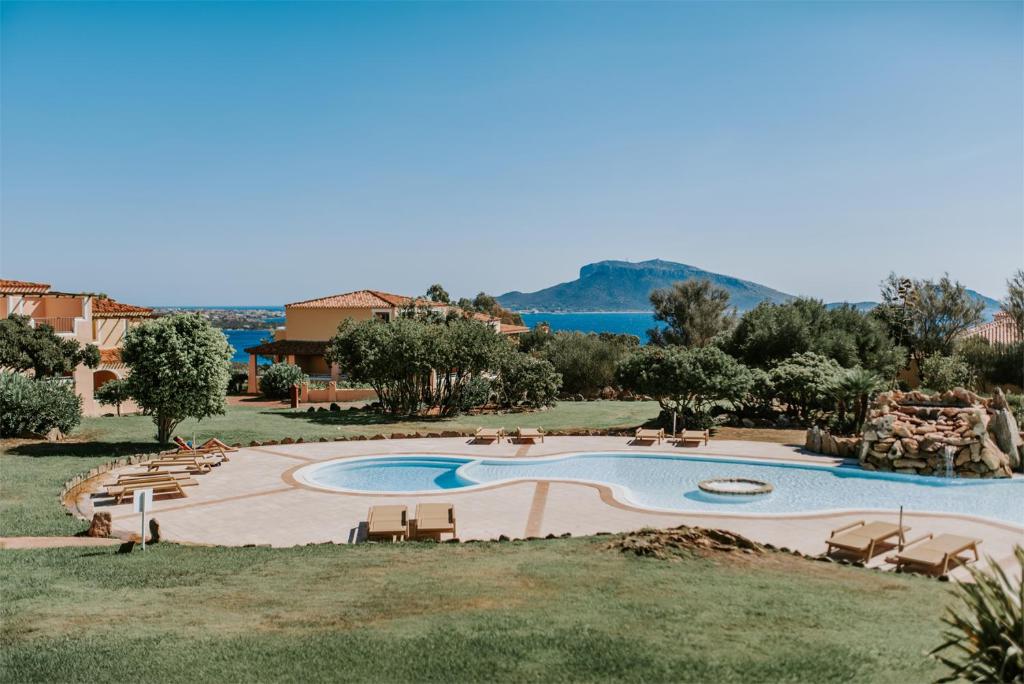 une grande piscine avec des chaises et un complexe dans l'établissement VOI Colonna Village, à Golfo Aranci