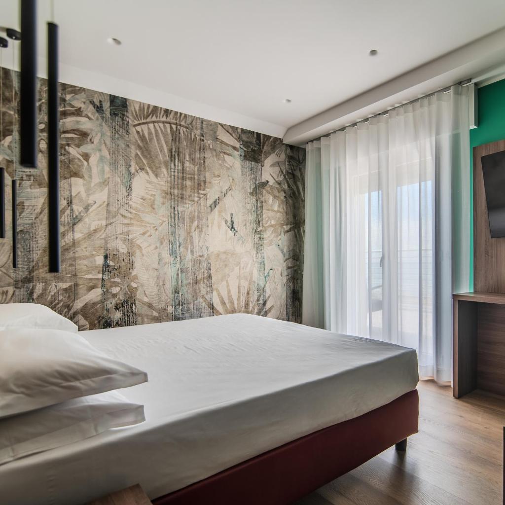 - une chambre avec un grand lit blanc et un mur dans l'établissement Hotel Cesare Augustus, à Lido di Jesolo