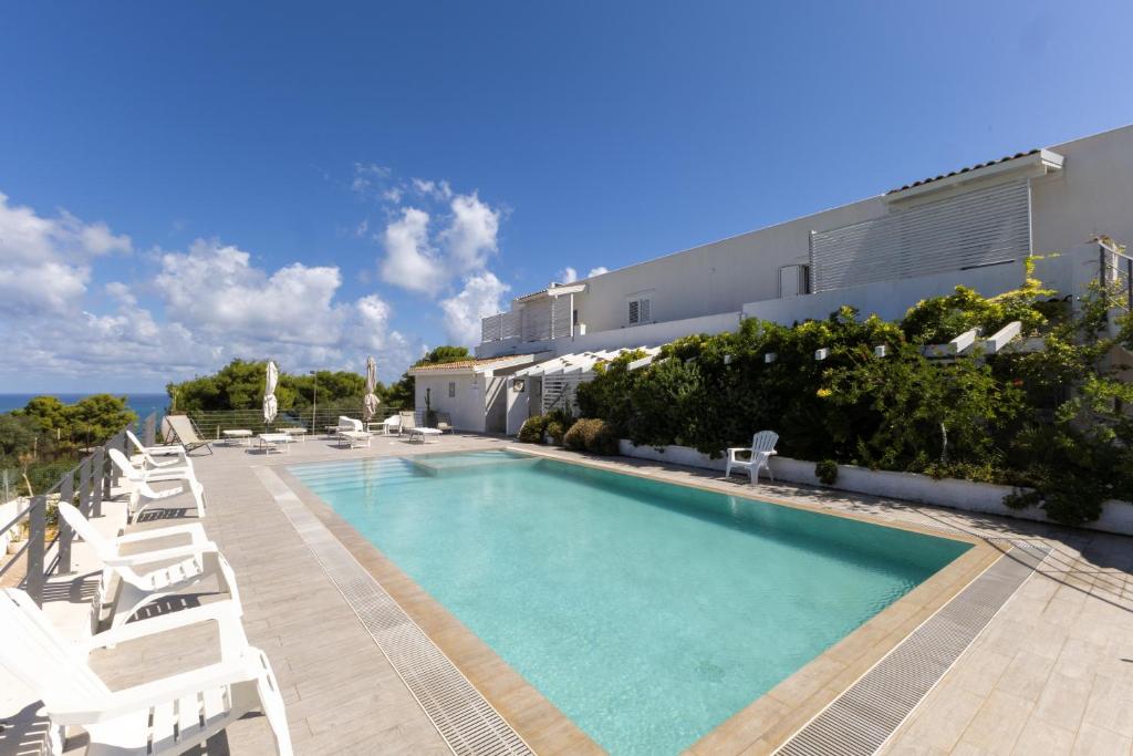 une piscine avec des chaises blanches et un hôtel dans l'établissement Maison Marie, à Vieste
