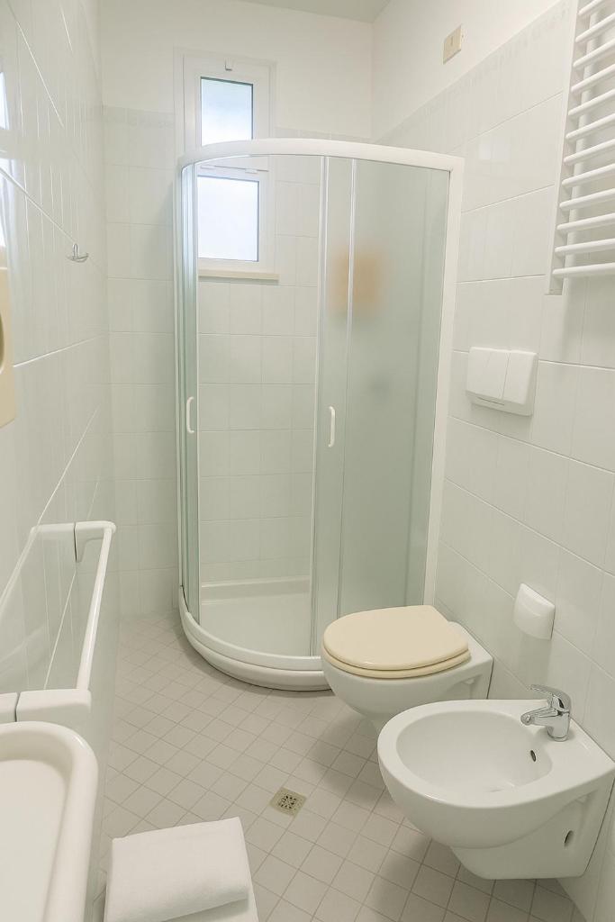 une salle de bain blanche avec douche et toilettes dans l'établissement Hotel Massimo, à Riccione 34 autres photos