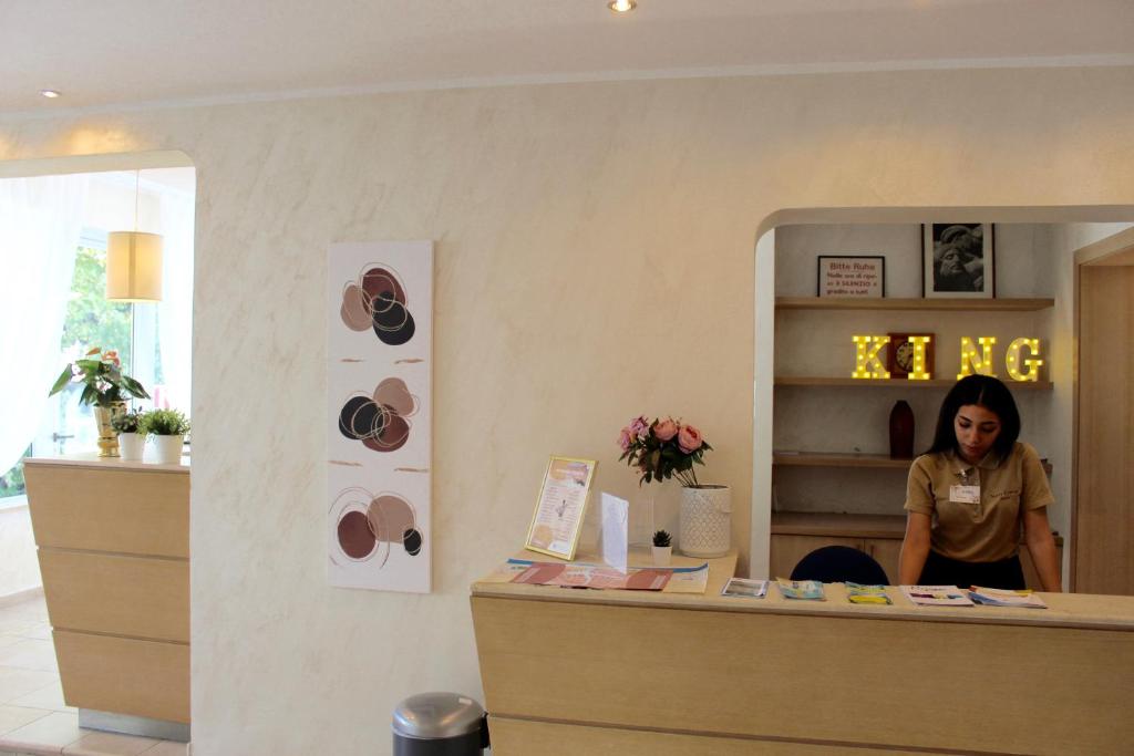 une femme se tenant derrière un comptoir dans un magasin dans l'établissement King Hotel, à Cesenatico
