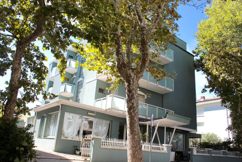 un bâtiment vert avec des arbres devant dans l'établissement King Hotel, à Cesenatico