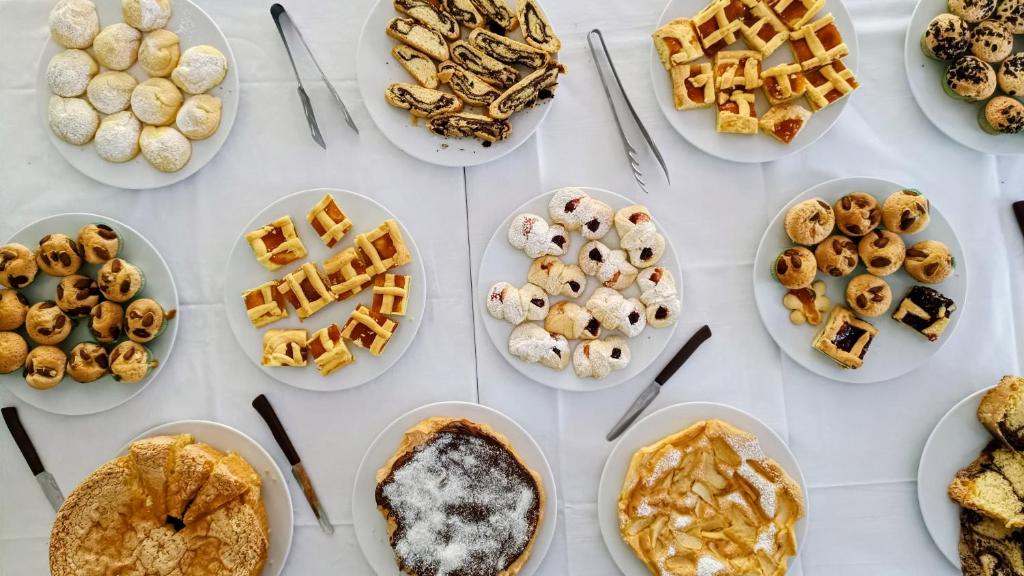 une table garnie d'assiettes de pâtisseries et de desserts dans l'établissement Hotel D'Atri, à Montesilvano