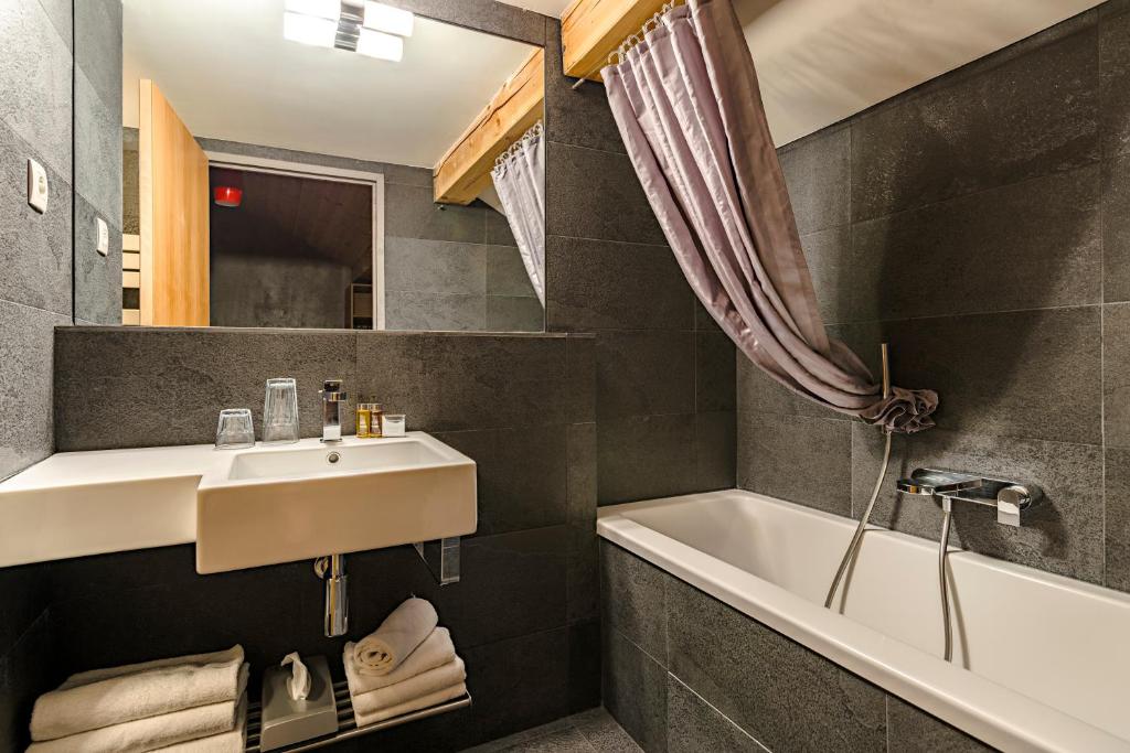 une salle de bain avec un lavabo et une baignoire dans l'établissement Anova Hotel & Spa, à Montgenèvre