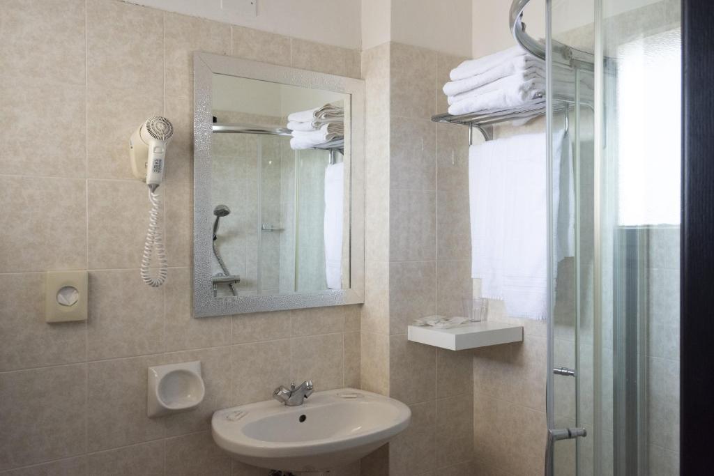 une salle de bain avec un lavabo, un miroir et une douche dans l'établissement Bikini Tropicana Family Hotel, à Lido di Savio