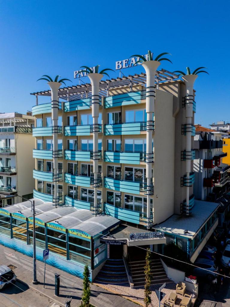 un bâtiment avec des palmiers devant dans l'établissement Hotel Palm Beach B&B SEA VIEW, à Rimini
