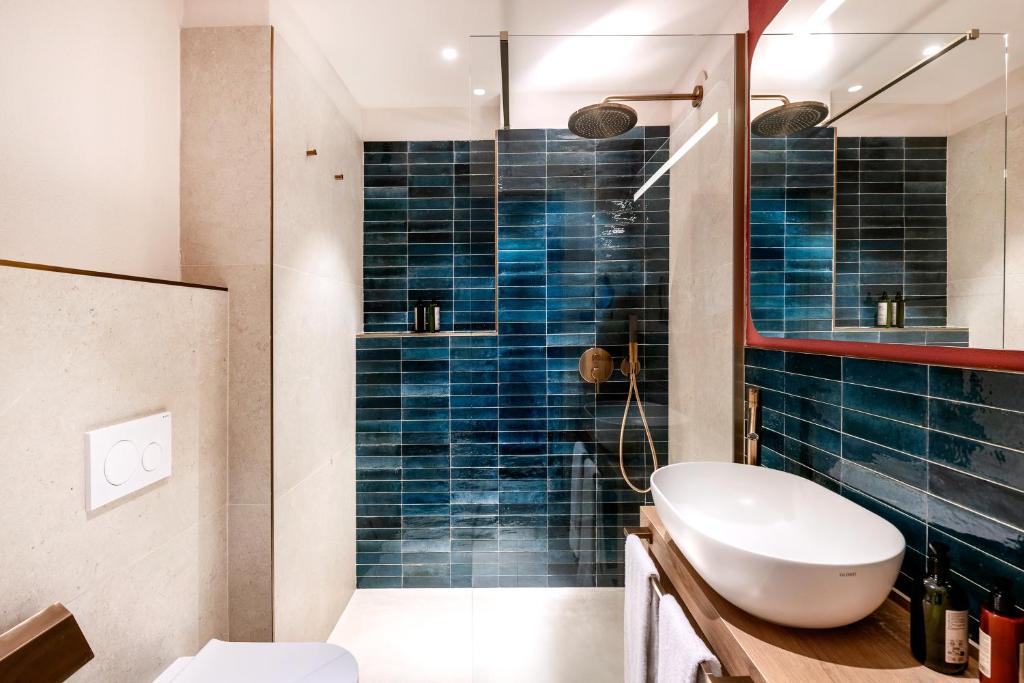 une salle de bain avec un lavabo et une douche avec du carrelage bleu dans l'établissement VOI Tanka Selected, à Villasimius