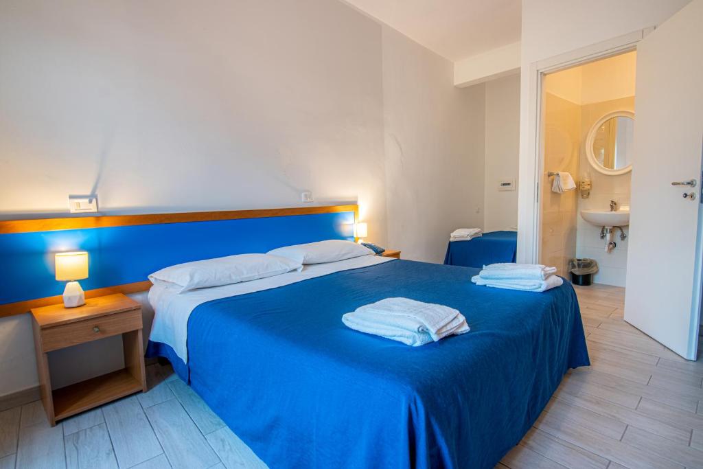 une chambre avec un lit bleu avec deux serviettes dessus dans l'établissement La Feluca, à Isca sullo Ionio